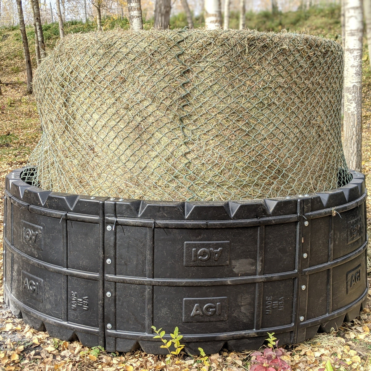 Horses eating a round bale from a poly hay ring